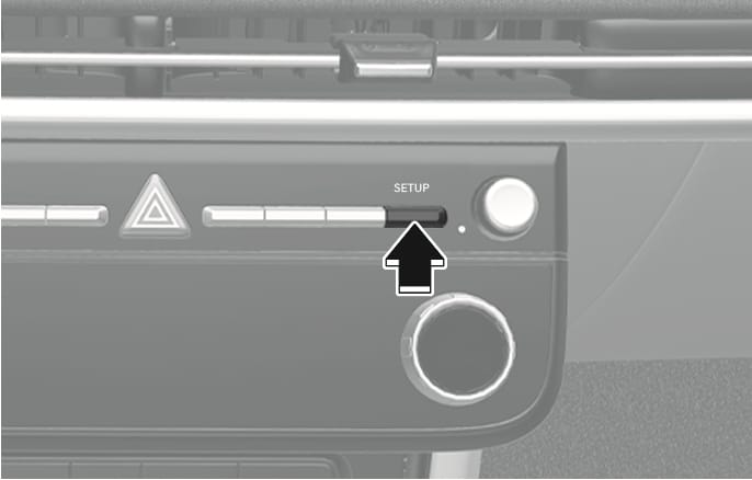 2025 Hyundai Tucson SETUP button image. A black arrow points upward to the 'SETUP' button on the center control panel, located to the right of the hazard light button. Explains the function of pressing the button to access the vehicle settings menu.