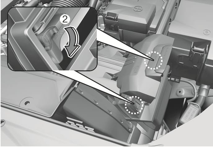 2025 Hyundai Tucson air cleaner filter replacement image. White dotted circles highlight the locking levers on the cover. An inset shows the lever (2) with a curved arrow indicating a downward motion. Explains the function of pulling down the lever to the unlock position.
