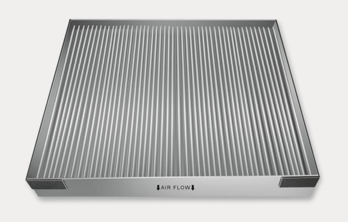 2025 Hyundai Tucson cabin air filter replacement caution image. A rectangular air filter with vertical pleats is shown. On the side panel, the text 'AIR FLOW' is printed with downward-pointing black arrows indicating the direction. Explains the correct installation orientation where the arrows must face downwards to prevent noise and increase effectiveness.