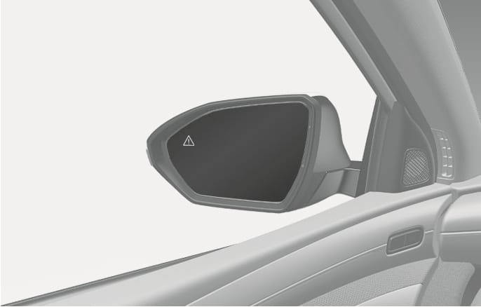 2025 Hyundai Tucson Blind-Spot Collision-Avoidance Assist warning light image. The image displays the driver's side outside rearview mirror with a triangular warning icon containing an exclamation mark illuminated on the mirror surface. Explains the collision warning function that alerts the driver when a vehicle is detected in the blind spot.