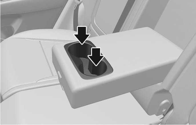 2025 Hyundai Tucson rear seat cup holder image. The rear center armrest is folded down, revealing two cup holder slots. Two black vertical arrows point downwards into the slots. Explains the function of placing cups or small beverages in the rear armrest cup holders.