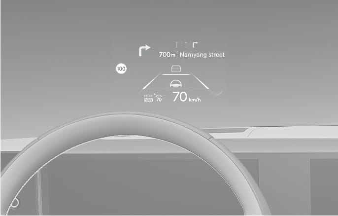 2025 Hyundai Tucson Head-up display (HUD) image. The view through the windshield shows projected information including '70 km/h' speed, a '100' speed limit sign, and navigation guidance to 'Namyang street' with turn arrows. Explains the function of displaying driving information within the driver's forward view.