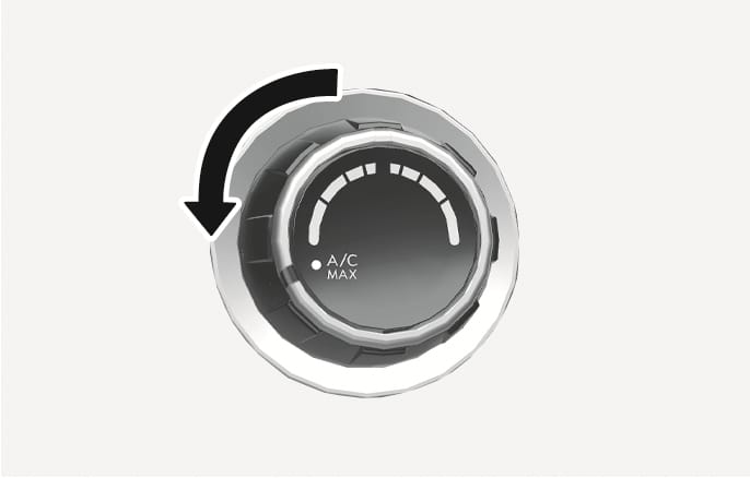 2025 Hyundai Tucson MAX A/C mode image. A curved black arrow indicates turning the temperature control knob counter-clockwise to the 'A/C MAX' position. Explains the function of activating the MAX A/C mode for rapid cooling.