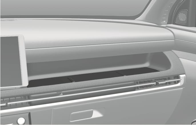 2025 Hyundai Tucson Front passenger seat open tray image. The image displays the long, open storage tray integrated into the dashboard on the passenger side, located above the air vents. It describes the function of storing small items.