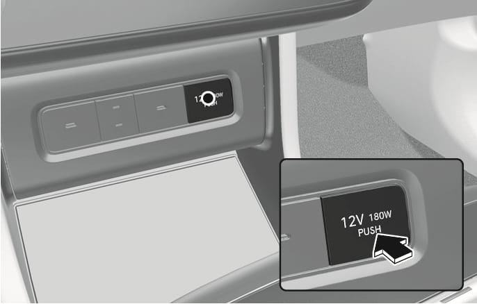 2025 Hyundai Tucson Power outlet Type A image. Shows the power outlet location and a close-up of the cover labeled '12V 180W PUSH'. A black arrow points to the cover, indicating the push action. Explains how to access the power outlet.