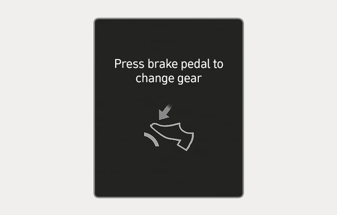 2025 Hyundai Tucson cluster display message image. The screen displays the text 'Press brake pedal to change gear' and an icon of a foot pressing a pedal with a downward arrow. This explains the warning message displayed when the brake pedal is not depressed while shifting the gear.