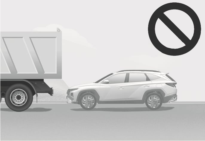 2025 Hyundai Tucson Remote Smart Parking Assist limitation image. A white SUV is positioned behind a large truck with high ground clearance, accompanied by a prohibition symbol. Explains the restriction on using the system around vehicles with high ground clearance, such as trucks or buses, to prevent accidents.