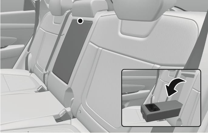 2025 Hyundai Tucson rear seat armrest image. The image shows the armrest located in the center of the rear seatback. An inset view with a black arrow indicates the action of pulling the armrest down to reveal cup holders. This describes the function of using the rear seat armrest.