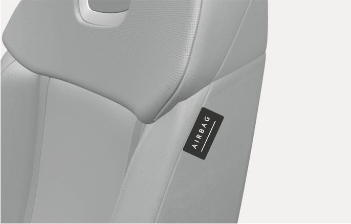 2025 Hyundai Tucson side airbag label image. A close-up view of the front seat backrest displays a black tag with 'AIRBAG' written in white text on the side seam. This indicates the location of the side airbag installed within the seat bolster.