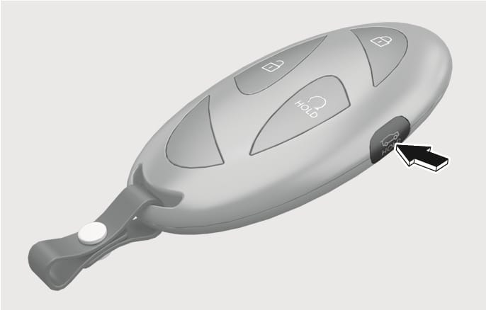 2025 Hyundai Tucson smart key power tailgate button image. A black arrow indicates the power tailgate open/close button on the side of the key fob, featuring a car icon with an open trunk and 'HOLD' text. Explains the function of pressing and holding the button to open or close the tailgate.