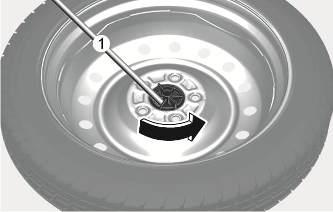 2025 Hyundai Tucson spare tire replacement Type A image. The jack handle (1) is inserted into the tire hold-down wing bolt at the center of the spare tire, with a black curved arrow indicating counterclockwise rotation. Explains the function of loosening the tire hold-down wing bolt using the jack handle.