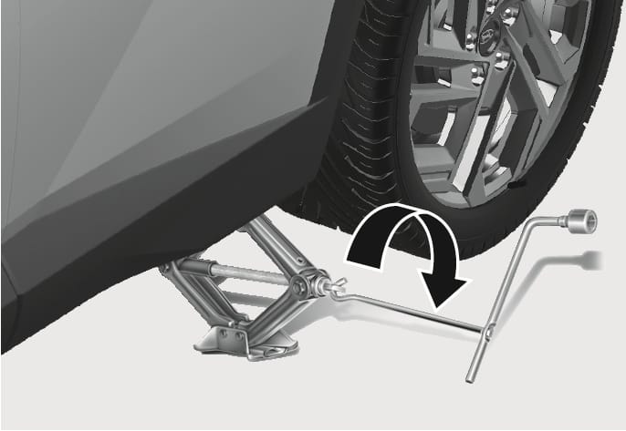 2025 Hyundai Tucson jack operation image. A scissor jack is placed under the vehicle frame with a jack handle inserted. A curved black arrow indicates turning the handle clockwise. Explains the function of raising the vehicle to change a tire.