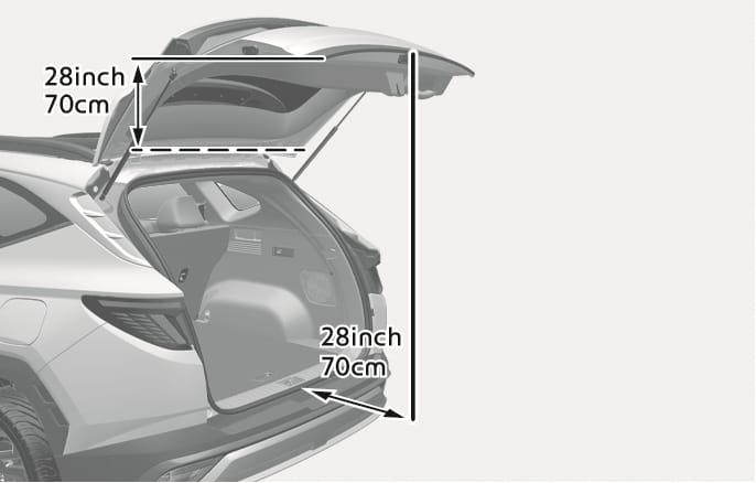 2025 Hyundai Tucson tailgate operating space image. The tailgate is fully open, and arrows indicate the required clearance. A vertical arrow shows 28 inches (70 cm) of space needed above the roof, and a horizontal arrow shows 28 inches (70 cm) of space needed behind the vehicle. Explains the minimum clearance required to safely operate the power tailgate.