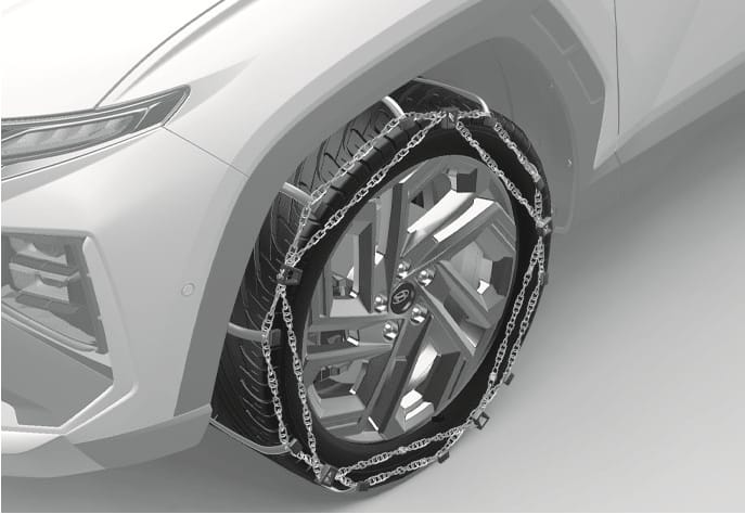 2025 Hyundai Tucson wire-type tire chain image. The image displays a metal wire chain installed on the front tire, covering the tread and sidewall in a cross pattern. Explains the appearance of properly mounted wire-type snow chains to ensure safe driving in snowy or icy conditions.