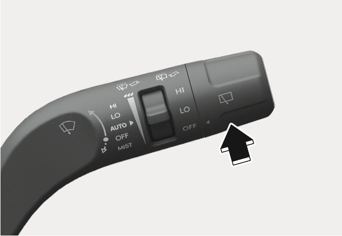 2025 Hyundai Tucson rear wiper and washer lever image. A black arrow points upwards, indicating the action of pushing the lever away from the driver. Describes the function of spraying rear washer fluid and operating the rear wipers.