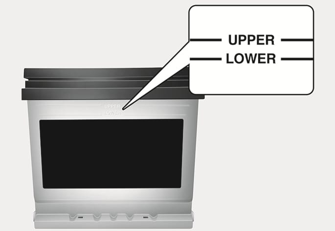 2025 Hyundai Tucson battery maintenance image. It displays the side of the battery with a magnified view of the 'UPPER' and 'LOWER' level markings. Explains the function of checking the electrolyte level to ensure it is between the specified maximum and minimum lines.