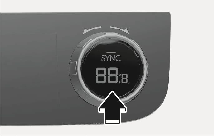2025 현대 투싼 공조 장치 SYNC 버튼 이미지입니다. 원형 노브 중앙에 'SYNC' 문구와 '88:8' 숫자가 표시되어 있습니다. 노브 상단에는 회전 화살표가, 하단에는 노브를 누르는 굵은 화살표가 있습니다. 버튼을 눌러 운전석과 동승석 온도를 동기화하는 기능을 설명합니다.