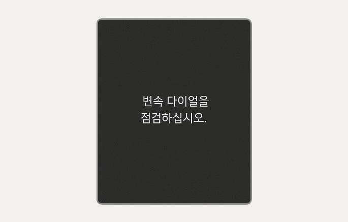 2025 현대 투싼 변속 다이얼 점검 경고문 이미지입니다. 클러스터 표시창의 검은색 배경 중앙에 '변속 다이얼을 점검하십시오.'라는 흰색 텍스트가 표시되어 있습니다. 변속 다이얼의 주요 기능에 이상이 있을 경우 운전자에게 정비소 방문 및 점검이 필요함을 알리는 화면 구성을 설명합니다.