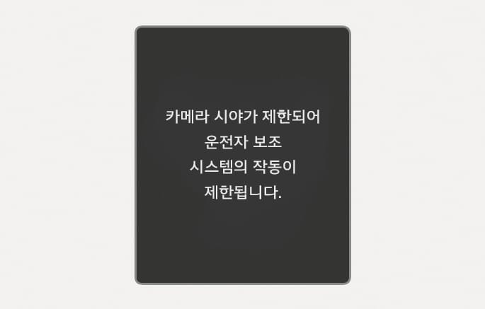 2025 현대 투싼 인식 센서 가림 경고 화면 이미지입니다. 어두운 배경의 클러스터 화면 중앙에 '카메라 시야가 제한되어 운전자 보조 시스템의 작동이 제한됩니다.'라는 흰색 문구가 표시되어 있습니다. 전방 카메라의 시야가 확보되지 않아 운전자 보조 시스템의 작동이 일시적으로 제한되는 상황을 운전자에게 알리는 기능을 설명합니다.