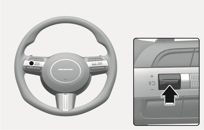 2025 현대 투싼 수동 속도 제한 보조 일시 해제 이미지입니다. 스티어링 휠 좌측에 위치한 조작 스위치의 위치와 상세 모습을 보여줍니다. 검은색 화살표가 스위치 중앙을 안쪽으로 누르는 동작을 지시하고 있습니다. 속도 제한 기능을 일시적으로 해제하기 위해 스위치를 누르는 기능을 설명합니다.