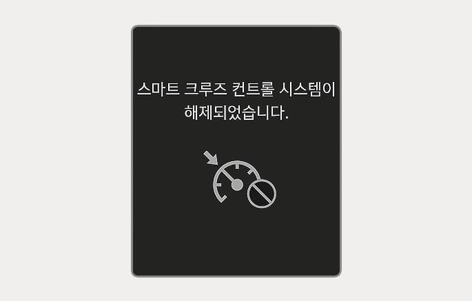 2025 현대 투싼 스마트 크루즈 컨트롤 시스템 해제 알림 화면 이미지입니다. 클러스터 화면 중앙에 '스마트 크루즈 컨트롤 시스템이 해제되었습니다.'라는 문구가 표시되어 있습니다. 하단에는 속도계 형상과 해제를 의미하는 원형 금지 아이콘이 그려져 있습니다. 시스템 작동이 해제되었음을 운전자에게 시각적으로 알리는 기능을 설명합니다.