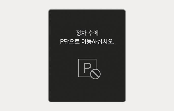2025 현대 투싼 클러스터 경고문 이미지입니다. 검은색 배경 화면 중앙에 '정차 후에 P단으로 이동하십시오.'라는 문구가 표시되어 있고, 하단에는 사각형 안의 'P' 심볼 위에 금지 기호가 겹쳐진 아이콘이 위치해 있습니다. 차량이 완전히 정차하지 않은 상태에서 P단으로 변속을 시도할 때, 정차 후 변속하도록 안내하는 기능을 설명합니다.