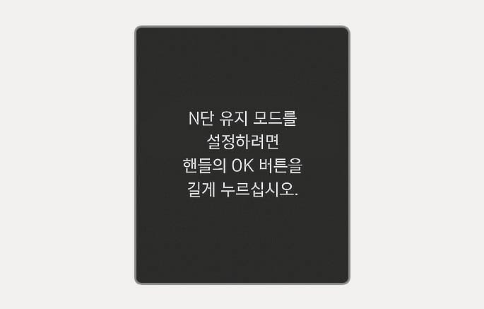 2025 현대 투싼 N단 유지 모드 안내 메시지 이미지입니다. 클러스터 화면 중앙에 'N단 유지 모드를 설정하려면 핸들의 OK 버튼을 길게 누르십시오.'라는 흰색 문구가 표시되어 있습니다. N단 유지 모드 진입을 위한 조작 방법을 안내하는 기능을 설명합니다.