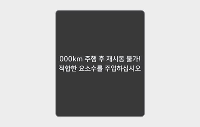 2025 현대 투싼 요소수 시스템 고장 경고문 이미지입니다. 계기판 화면에 '000km 주행 후 재시동 불가! 적합한 요소수를 주입하십시오'라는 흰색 텍스트가 표시되어 있습니다. 비정상 요소수가 감지되어 재시동이 불가능한 상태임을 알리는 기능을 설명합니다.