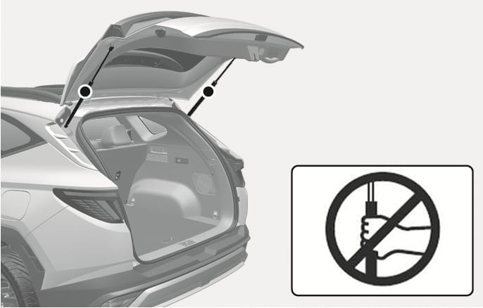 2025 현대 투싼 테일게이트 가스리프터 취급 주의 이미지입니다. 테일게이트가 열린 상태에서 양쪽을 지지하는 가스리프터의 위치가 표시되어 있고, 우측 하단에는 가스리프터를 손으로 잡는 동작 위에 금지 기호가 표시된 아이콘이 있습니다. 부품 변형 및 안전사고 예방을 위해 테일게이트 지지 부품을 잡지 않도록 경고하는 기능을 설명합니다.